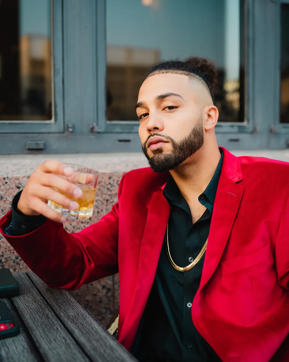 A guest in a red velvet blazer raising a whiskey